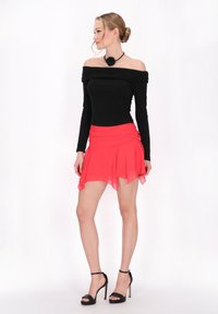 Schwarzes schulterfreies Top, pinkfarbener ausgestellter Minirock mit Raffung, elegante schwarze High-Heels, glattes Material und fließendes Design.