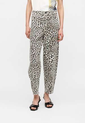 Woman wearing high-waisted, tapered leopard print pants paired with black open-toe heels with a buckle detail.