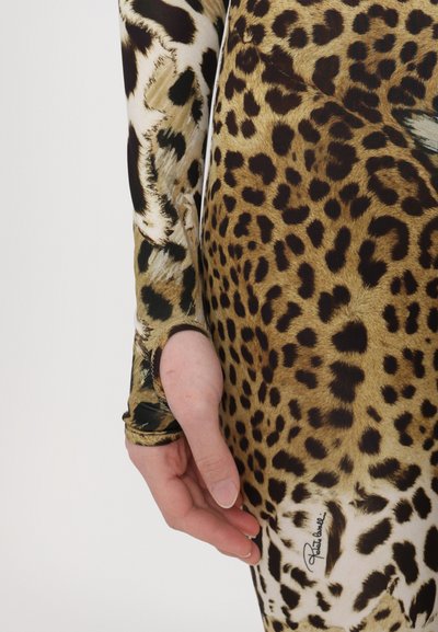 Dolga majica z leopardjim motivom in prilegajočim dizajnom. Narejena iz gladkega blaga, vsebuje luknjico za palec in natisnjeni logotip blizu roba.