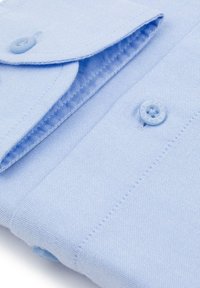 Jasnoniebieska koszula zapinana na guziki z teksturowanej tkaniny, z klasycznym kołnierzykiem i jasnoniebieskimi guzikami. Widać staranne detale przeszyć.