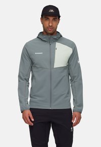 Lys grå zip-up jakke med en kontrasterende bleg grøn brystpanel, lavet af tekstureret stof, med hætte og sidelommer.