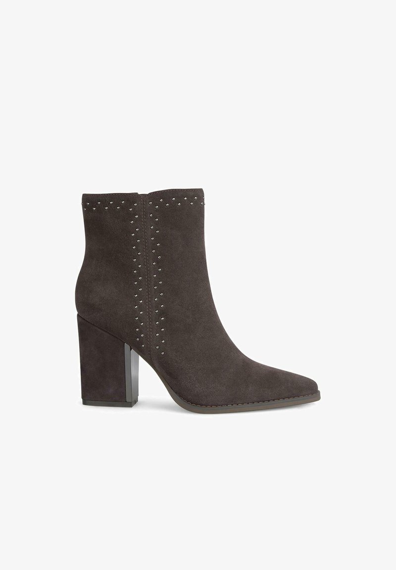 Botas de ante gris oscuro hasta el tobillo con punta afilada, adornadas con tachuelas plateadas en los costados y un tacón grueso con un acabado brillante.