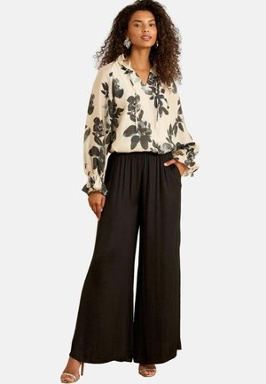 Floral blouse in cream with black and teal flowers, paired with wide-leg black pants. Features a relaxed fit and elastic waistband.