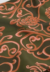 Green fabric featuring a floral pattern in pink, with swirling vines and leaves, marked with "farm rio" in a subtle script.
