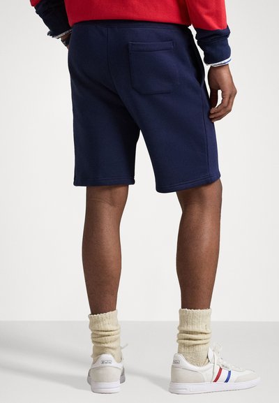 Jūras spēku šorti ar aizmugurējo kabatu, valkāti ar baltām kedām un krēmkrāsas zeķēm. Ikdienišķs dizains un ērta piegriezuma.