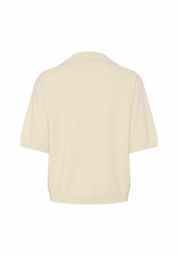 Lyhythihainen, kermaisen valkoinen polo-paita, jossa on pehmeä ja teksturoitu kangas sekä klassinen kaulus. Yksinkertainen muotoilu rentoa istuvuutta varten.