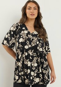 Sort V-hals top med korte ærmer, med et blomstermotiv i cremefarver. Blødt stof med en løs, afslappet pasform og indsamlede detaljer.