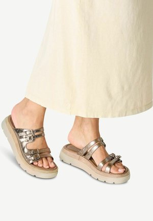 Sandalias de bronce metálico con múltiples correas ajustables, que cuentan con una suela gruesa de color crema y una plantilla texturizada para mayor comodidad.