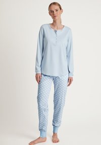 Lichtblauw katoenen long-sleeve top met een knoopsluiting bij de hals, gecombineerd met lichtblauwe polka dot broek met aansluitende boorden bij de enkels.