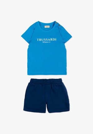 T-shirt blu a maniche corte Trussardi Milano 1911 con due bottoni sulle spalle abbinata a pantaloncini blu scuro con vita elasticizzata.