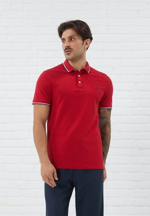 Punane polo särk, mis on valmistatud puuvillast, kolme nupuga krae ja sinise ja valge kontrastiga krae ning käiste ääred, sisaldab väikest logo.