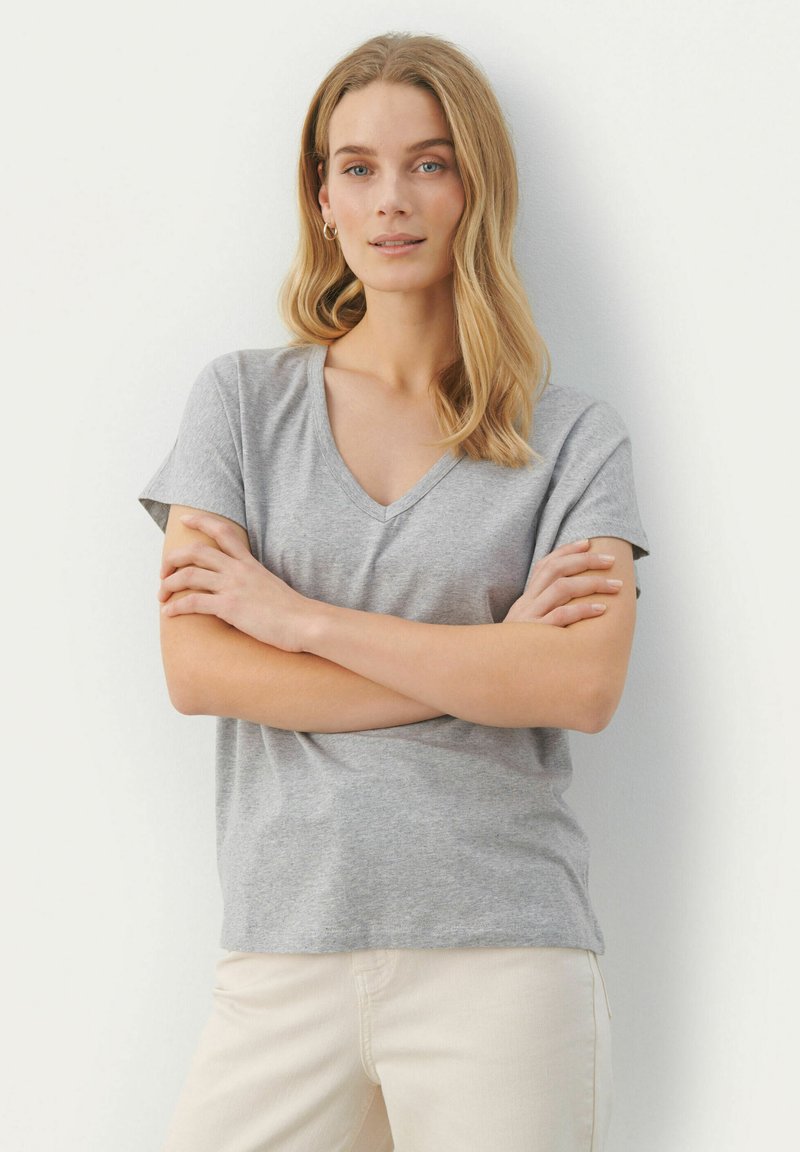Grå V-ringad t-shirt i mjukt tyg, med korta ärmar och avslappnad passform, bärs med krämfärgade byxor.