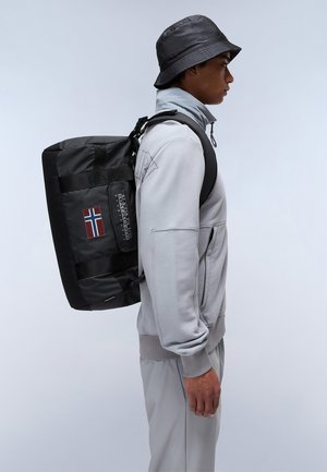 Black waterproof backpack featuring a side patch with a Norwegian flag, adjustable straps, and textured material. Worn on the side of a person.