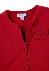 Rode katoenen ritsjack met een ronde halslijn en een bevestigde stoffen bloemenaccent met een knop in het midden. Matenlabel inbegrepen.
