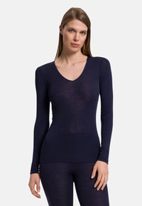 Mörkblå långärmad topp i mjukt, lätt material; har en djup V-ringning och en figurnära silhuett som ger ett smidigt utseende.