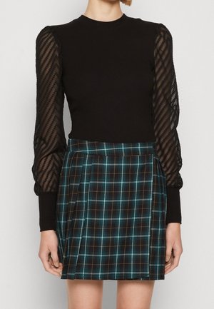 Haut noir avec manches transparentes rayées texturées, associé à une minijupe plissée à carreaux dans des tons de bleu sarcelle, noir et orange.