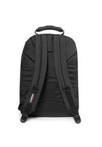 Mochila negra con correas acolchadas y un asa en la parte superior, hecha de una tela duradera con una textura suave y un acento de logo cerca de la base.