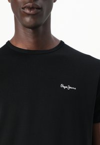 T-shirt nera a maniche corte realizzata in cotone morbido, con logo "Pepe Jeans" ricamato nella zona sinistra del petto.