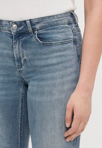 Világoskék farmernadrág, klasszikus egyenes szabással, öt zsebbel és enyhe kopással. Fém gombos záródással rendelkezik.