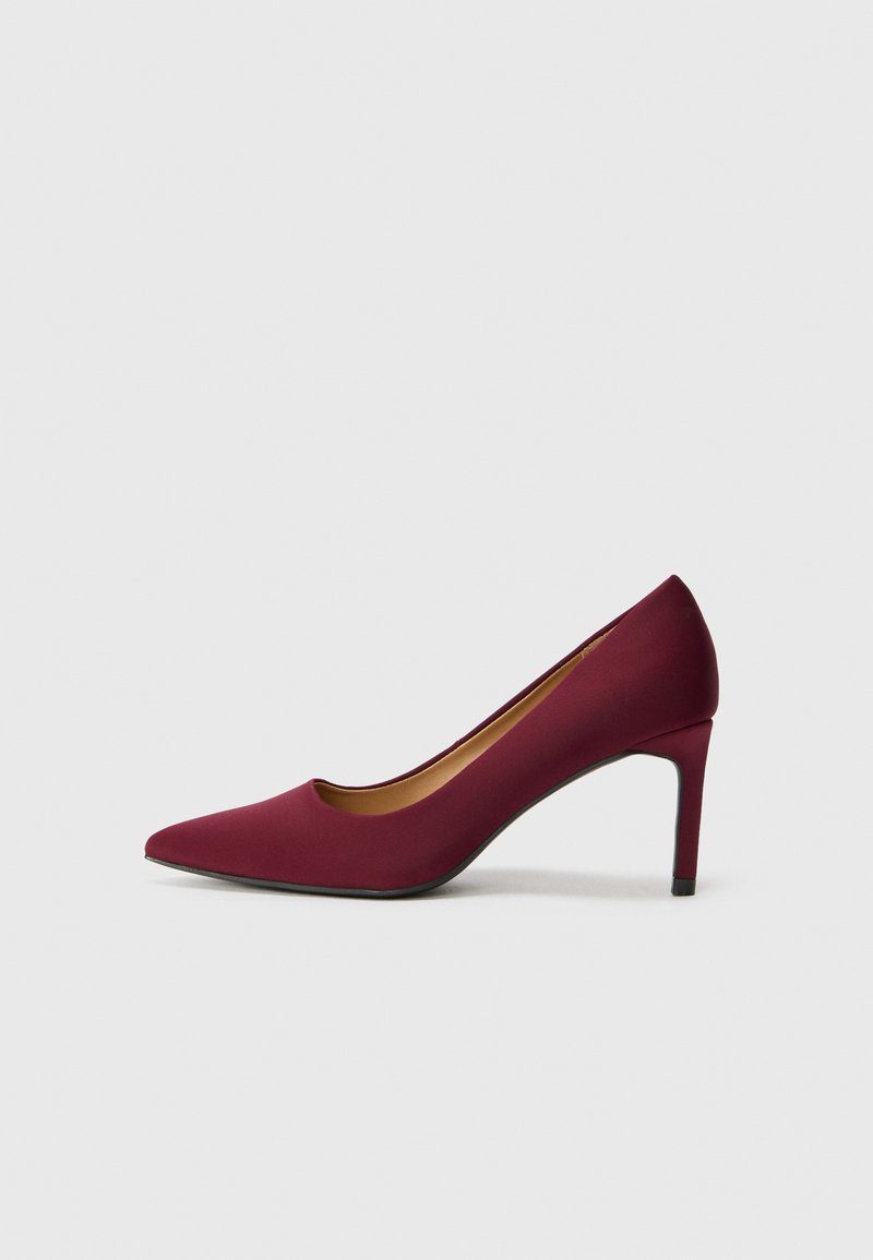 Pump bordeaux con tacco alto, punta affilata, texture liscia, parte anteriore a taglio basso e tacco a stiletto sottile. Design minimalista.