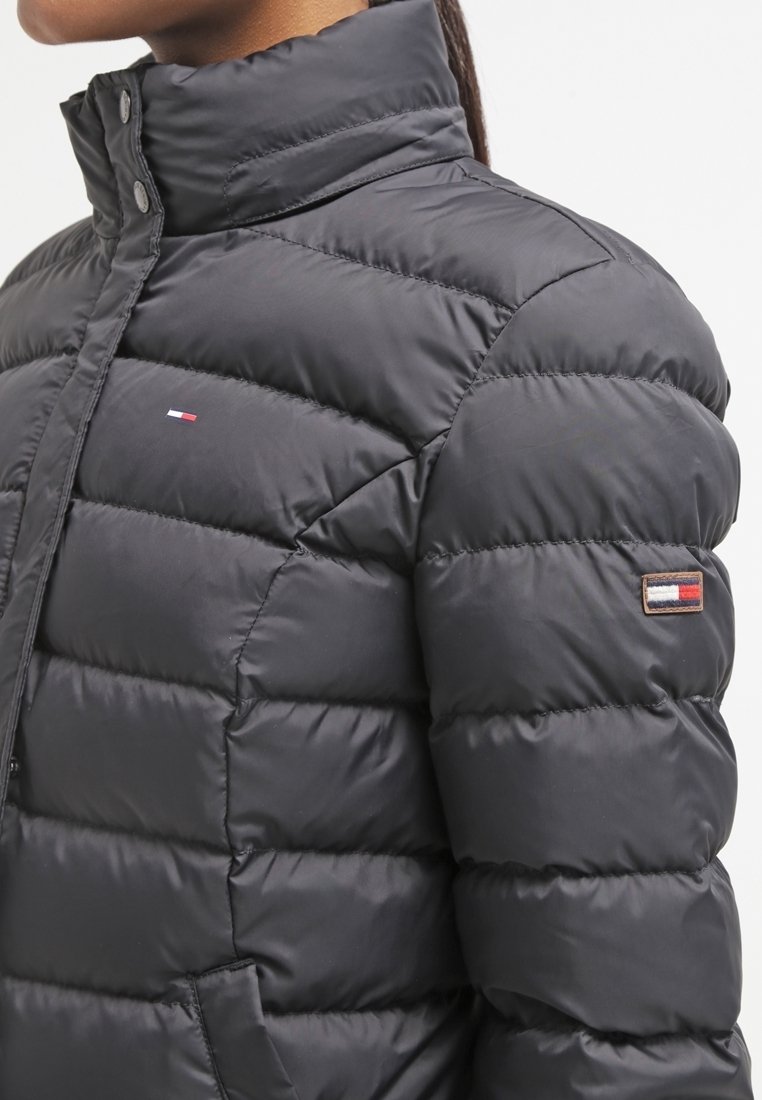 Černá prošívaná bunda s vysokým límcem, prošívanou texturou a malým logem na prsou. Nabízí přiléhavý střih a hladký, lesklý povrch.