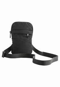 Sac à bandoulière noir en tissu avec une surface texturée, fermeture zippée et sangle réglable. Dispose d'une poche avant pour un rangement supplémentaire.