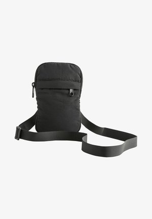 Bolso bandolera negro de tela con una superficie texturizada, cierre de cremallera y correa ajustable. Presenta un bolsillo frontal para almacenamiento adicional.