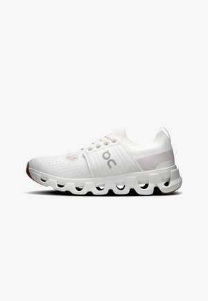 Chaussure de sport blanche avec une tige en mesh texturé, des accents gris clair, et un design de semelle segmentée distinctif. Dotée de lacets traditionnels.