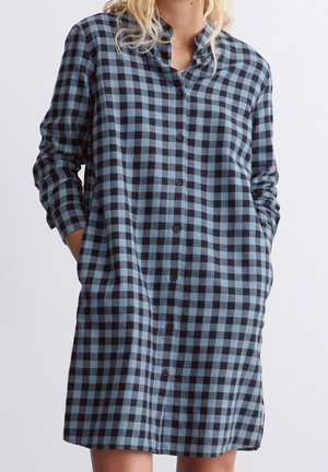 Overhemdjurk met knopen in blauw-zwart geblokt patroon. Lange mouwen, losse pasvorm, met kraag en zijzakken. Zachte stoftextuur.