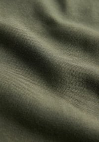 Detailný záber na olivovo zelenú látku s jemnou pletenou textúrou a miernymi záhybmi.