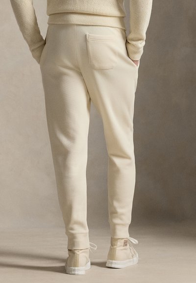 Μπεζ αθλητικό παντελόνι με στενή εφαρμογή, διαθέτει πίσω τσέπη, ριμπ μανσέτες και κορδόνι στο κάτω μέρος των ποδιών, κατασκευασμένο από απαλό ύφασμα.