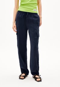 Pantalons légers bleu marine avec une taille élastique, cordon de serrage ajustable et poches cargo latérales ; texture lisse avec une coupe décontractée.