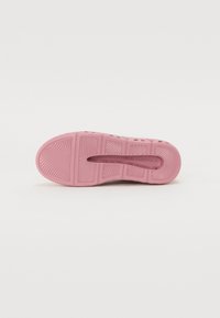 Roze rubberen sneakersole met gripgroeven en branding, met een textuurpatroon over het oppervlak voor een verbeterde grip.