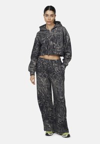 Felpa corta e pantaloni a gamba larga in un motivo camouflage nero e grigio. Realizzati in materiale morbido con una vestibilità rilassata e vita elastica.