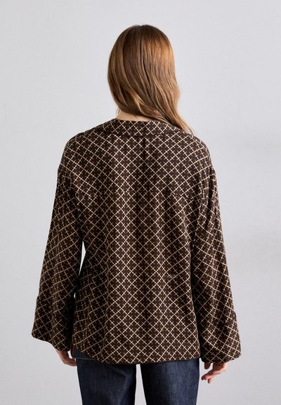 Brun mønstrete bluse med løs passform, klokkeermer og krage, med et geometrisk design i beige. Bakvisning vist.