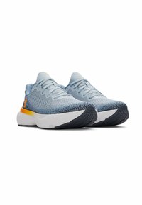 Chaussures de sport bleu clair avec une tige en tissu texturé, une semelle intermédiaire blanche et une semelle extérieure noire avec des accents orange près du talon.