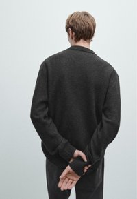 Tmavě šedý pletený svetr s kulatým výstřihem a žebrovanými manžetami, s pohodlným střihem a hladkou strukturou, zobrazený zezadu.
