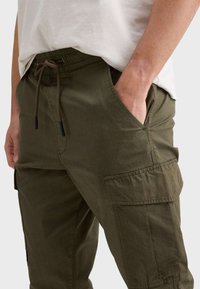 Cargo broek in olijfgroen katoen, met een elastische tailleband met trekkoord, zijzakken en een gestructureerde stof.
