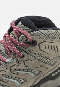 GORE-TEX tursko med sko med grå mesh overdel og brune semsket skinnfiner, rosa og hvite mønstrede lisser, og svart polstret krage.