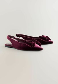 Burgundowe aksamitne buty typu slingback z wąskim noskiem, ozdobione dużą kokardą z przodu i małym obcasem. Gładka tekstura, elegancki design.