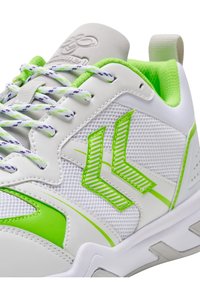 Scarpa sportiva bianca con tomaia in rete e dettagli verdi, finiture testurizzate e lacci decorati. Logo prominente sulla linguetta.