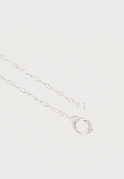 Λεπτό ασημένιο κολιέ αλυσίδας με επιμηκυμένους οβάλ κρίκους και μεγάλο κυκλικό κούμπωμα σε λευκό φόντο.