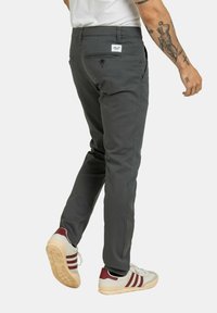 Graue Leggings im Slim-Fit, mit einem dezenten Taillentag, Gesäßtaschen und einer glatten, strukturierten Stoffoberfläche.