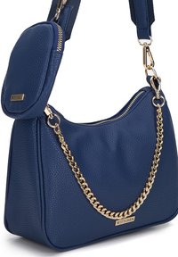Sac à épaule en cuir bleu avec accent en chaîne dorée, finition texturée, forme arrondie et pochette zippée détachable. Logo de la marque visible.