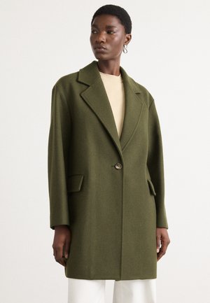 Cappotto in misto lana verde oliva con design sartoriale, ampie rever a punta, chiusura con un solo bottone e tasche laterali. Texture liscia.