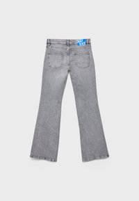 Grå utsvängda jeans med en texturerad denimfinish, som har två bakfickor och en blå märkesmidja.