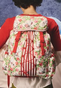 Rugzak met bloemenpatroon op een witte basis, met rode accenten, gestreepte details en zijzakken. Verstelbare riemen en gesp sluitingen.