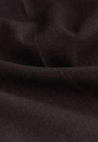 Tmavě hnědá tkanina s jemnou jemně zúženou strukturou, zobrazená v měkkých záhybech a vráskách, které zdůrazňují její hladký povrch.