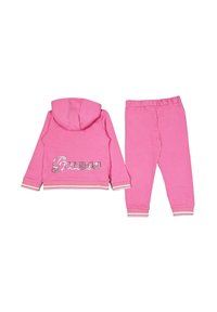 Completo tuta rosa con felpa con cappuccio e zip, dotata del logo argento "Guess", e pantaloni coordinati con cintura elastica e caviglie a costine.