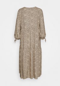 Mönstrad klänning i lätt tyg, med en beige bas och svarta fläckar, långa puffärmar och en lager-på-lager, flödande design.